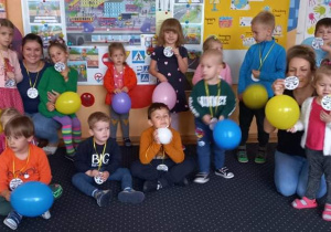 Dzień Przedszkolaka. Na zdjęciu widać 2 panie oraz dzieci trzymające kolorowe balony oraz medale.